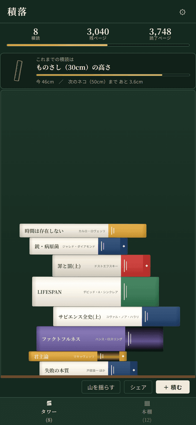 積落アプリのタワー画面。積読の本が物理演算で積み上がっている様子